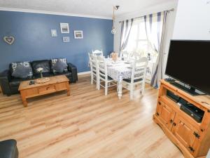 a living room with a couch and a table and a television at Driftwood House in Saundersfoot