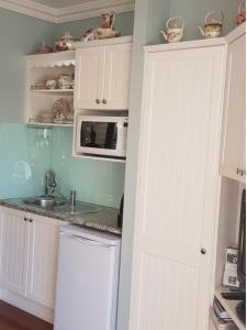 een keuken met witte kasten en een magnetron bij Reid's Place in Redcliffe