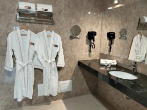 SM HOTEL Plus في ليما: حمام به روب ابيض على كاونتر ومغسلة
