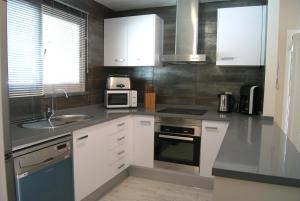 a kitchen with white cabinets and a sink and a microwave at Pomera III - BTB in Beniarbeig