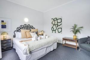 a bedroom with a large white bed and a chair at Leumeah - A Modern Townhouse in Cairns in Cairns North