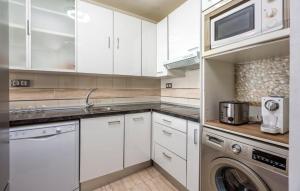 a kitchen with white cabinets and a washer and dryer at Surf house in Benalmadena Costa