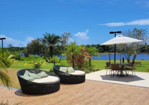 a patio with two chairs and a table and an umbrella at Lindo flat, na beira do lago, na melhor praia da Bahia in Guarajuba