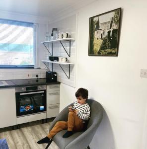 a young boy sitting in a chair in a kitchen at Studio Flat in Largs