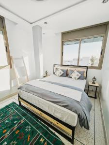 a bedroom with a large bed and two windows at cactus surf house in Tamraght Ouzdar