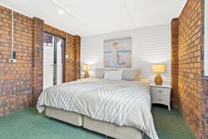 a bedroom with a bed and a brick wall at Deco Beach - 9 Cedar Street in Evans Head +12 photos