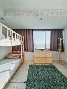 a bedroom with bunk beds and a large window at cactus surf house in Tamraght Ouzdar