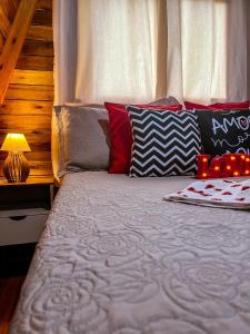 uma cama com almofadas vermelhas e pretas e um candeeiro em Morada do Corujão - Sossego das Águas em Praia Grande