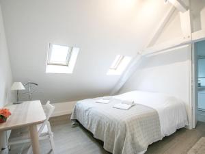 a white bedroom with a bed and a table at Calm and comfortable apartment in Bayeux, 9km from the beach in Bayeux