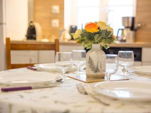a table with plates and glasses and a vase with flowers at Calm and comfortable apartment in Bayeux, 9km from the beach in Bayeux