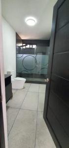 a bathroom with a toilet and a door to a room at De León Huehuetenango in Las Victorias