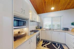 una cocina con armarios blancos y fregadero en 'Winterbrook' en Caboolture