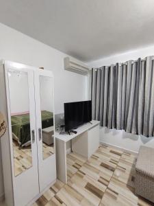 a white living room with a television and a desk at Pequeno apartamento em chacara próximo às praias com internet in São Francisco do Sul