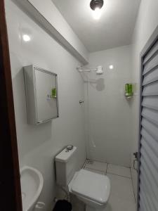 a white bathroom with a toilet and a sink at Pequeno apartamento em chacara próximo às praias com internet in São Francisco do Sul
