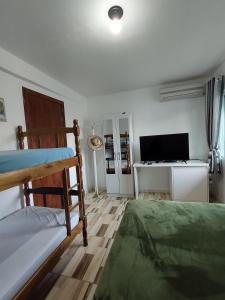 a bedroom with a bed and a desk with a television at Pequeno apartamento em chacara próximo às praias com internet in São Francisco do Sul