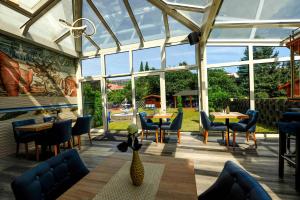 un giardino d'inverno con tavoli, sedie e finestre di Hotel Opal ad Hannover