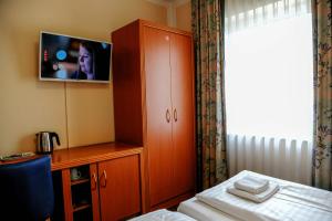 a bedroom with a cabinet with a tv on it at Hotel Opal in Hannover