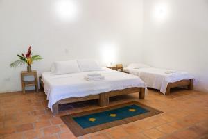 Casa Taller El Boga في Mompós: سريرين في غرفة بجدران بيضاء