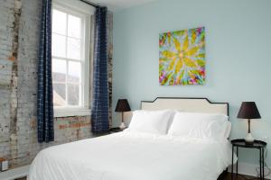 a bedroom with a white bed and a painting on the wall at Bischoff Inn - Former 1870 Furniture Factory Now 5 Room Boutique Hotel 