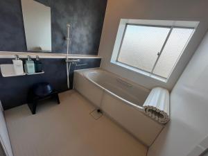 a bathroom with a bath tub and a window at HOSTEL OE in Yoshinogawa