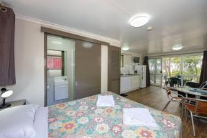 a bedroom with a bed and a kitchen and a table at Cape Hillsborough Nature Tourist Park in Seaforth
