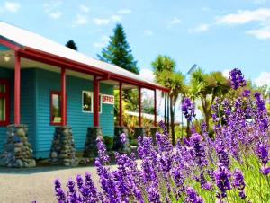 um edifício azul com flores roxas em frente em Adventure Lodge and Motels and Tongariro Crossing Track Transport em National Park