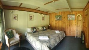 Blackfern Lodge في Waimiha: غرفة نوم فيها سرير وكرسي