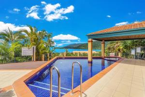 a swimming pool with a gazebo and the ocean at Aqua Vista in Airlie Beach