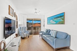 a living room with a couch and a tv at Aqua Vista in Airlie Beach