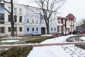 a snow covered street in front of a building at Pod Ratuszem in Wieluń