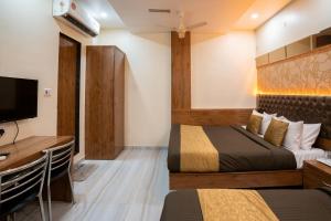 a bedroom with two beds and a desk and a tv at Hotel Royce Executive Near US Consulate, Bandra Kurla Complex in Mumbai
