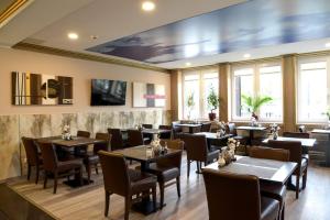 un restaurante con mesas, sillas y ventanas en Alexander Business Hotel Hannover City en Hannover