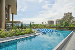 a swimming pool with blue lounge chairs on a building at Citadines Connect Rochester Singapore in Singapore
