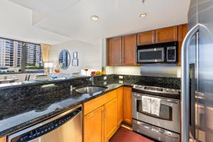 a kitchen with wooden cabinets and a stainless steel refrigerator at Aqua Palms Renovated 1BR, City View, Swimming Pool in Honolulu