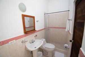 Un baño con lavabo, inodoro y espejo. en Hotel Villa Luna, en Villa de Leyva