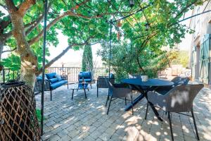 d'une terrasse avec une table et des chaises sous un arbre. dans l'établissement Dentelles Confidentielles, à Lafare