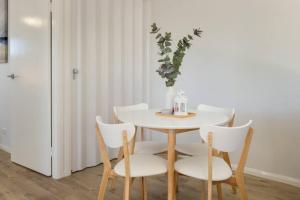 una mesa blanca con sillas blancas y una mesa con una botella. en Hummingbird Apartments 4264 Tor, en Rockville