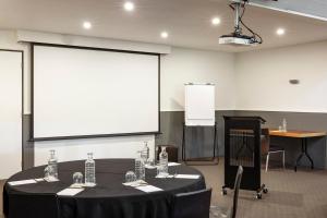 uma sala de conferências com uma mesa preta e um ecrã em Mineral Springs Hotel Hepburn em Hepburn Springs