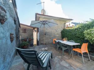 un patio con mesa, sillas y sombrilla en Belvilla by OYO Casa Pascoso, en Pescaglia
