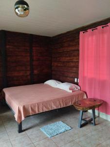 1 dormitorio con cama y cortina rosa en Cabaña Dalia, en Fortuna
