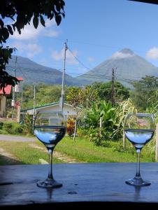 two wine glasses sitting on a table with a mountain in the background at Cabaña Dalia in Fortuna