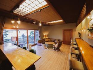 Habitación con mesa, sillas y sofá en 古民家ゲストハウス CHACHACHA AWAJI en Awaji