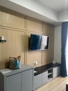 a living room with a tv on a wall at Luxury Apartemen Grand Lagoon Sungkono Surabaya in Dukuhpakis