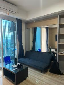 sala de estar con sofá azul y mesa de cristal en Luxury Apartemen Grand Lagoon Sungkono Surabaya, en Dukuhpakis