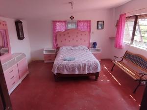 a bedroom with a pink bed and a bench at Finca la mora in Morelia