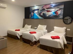 a hotel room with three beds and a tv at Hype Motorsport Hotel Nilai in Nilai
