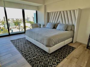 a large bed in a room with large windows at Moderno Bien Ubicado , Piscina A97c in Guadalajara