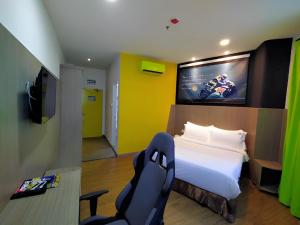 a bedroom with a bed and a tv and a chair at Hype Motorsport Hotel Nilai in Nilai
