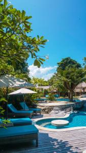 uma piscina com cadeiras azuis, guarda-sóis e árvores em Hai Tide Beach Resort em Nusa Lembongan