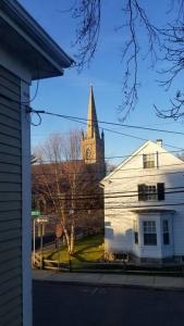 a church steeple and a white house with a church at Charming Townhouse in Historic Town near Boston. in Dedham